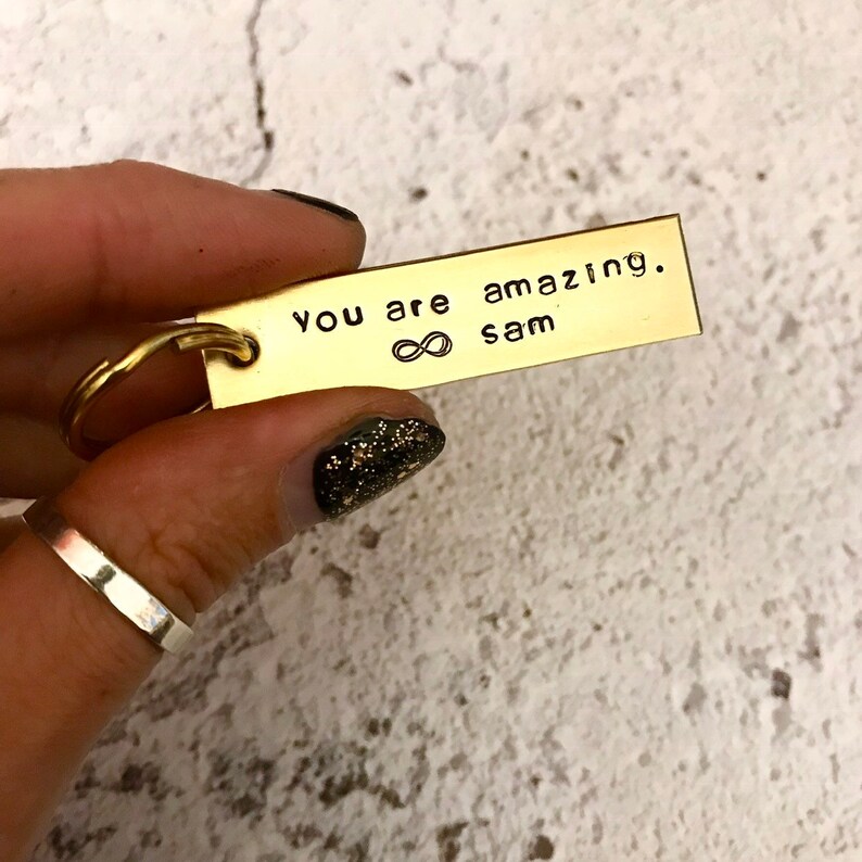 May include: Gold keyring with the text "You are amazing. Sam" and an infinity symbol.