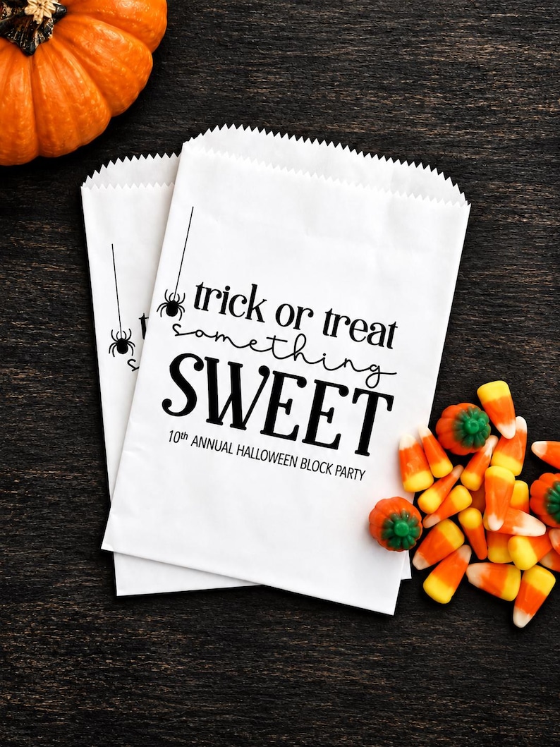 May include: Two white paper bags with serrated top edges featuring black text that reads trick or treat something SWEET 10th ANNUAL HALLOWEEN BLOCK PARTY and a small spider graphic hanging from a vertical line on the left side of the bags.