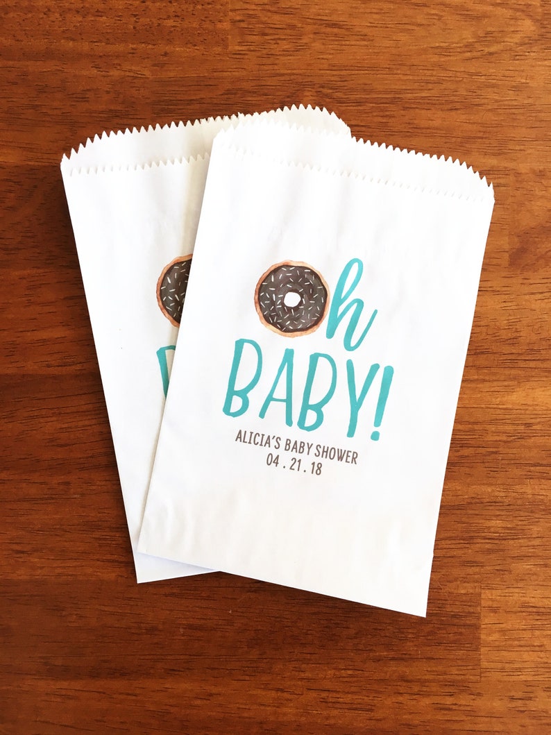 May include: Two white paper bags with a blue and white donut graphic and the text "Oh Baby!"  Alicia's Baby Shower 04.21.18