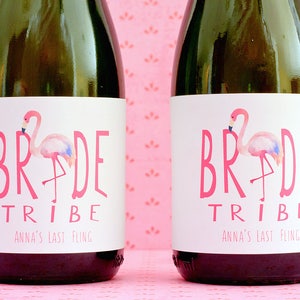 May include: Two champagne bottles with pink labels that say "Bride Tribe" and "Anna's Last Fling". Each label features a pink flamingo illustration.