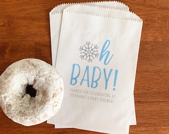 May include: White paper favor bags with a blue snowflake and the text "Oh Baby!"  Thanks for celebrating at Stephanie's Baby Shower!