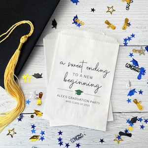 May include: White paper favor bag with black text that reads "a sweet ending to a new beginning" with a green graduation cap icon. The text "ALEX'S GRADUATION PARTY WHS CLASS OF 2025" is below the icon.