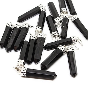 Könnte beinhalten: Eine Gruppe von schwarzen Obsidian-Kristallanhängern mit silberfarbenen Metallkappen. Die Anhänger sind in Form von langen, dünnen Spitzen geformt.