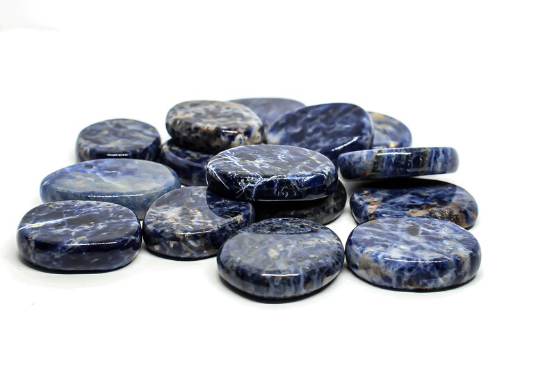 Pode incluir: Uma cole&ccedil;&atilde;o de pedras de sodalita azul lisas de forma oval. As pedras t&ecirc;m um padr&atilde;o marmorizado de azul claro e escuro.