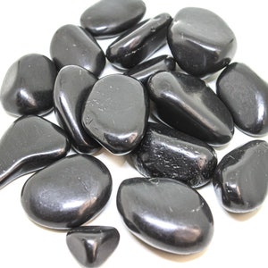 May include: A collection of smooth, black tumbled stones. The stones are various sizes and shapes, with a glossy finish.