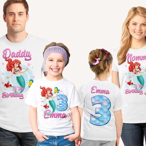 May include: White t-shirts with a mermaid and fish design. The shirts say "Daddy of the Birthday Girl", "Mommy of the Birthday Girl", and "Emma 3".