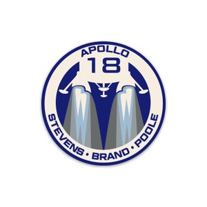 May include: A blue and white circular patch with the text "APOLLO 18" and the names "STEVENS, BRAND, POOLE" around the edge. A white lunar module with a blue number "18" is in the centre.
