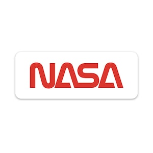Op de afbeelding: Een witte rechthoekige sticker met het woord "NASA" in rode letters.