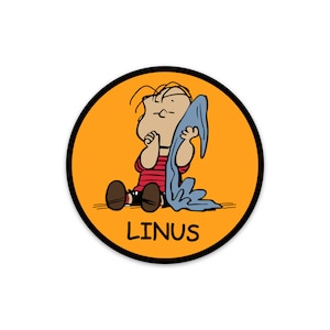 May include: A yellow circle with a black outline features a cartoon illustration of Linus from Peanuts. He is sitting with his blue blanket and looking up. The text "LINUS" is printed in black below him.
