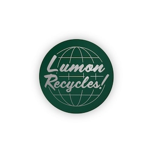 Puede incluir: Un círculo verde con un gráfico de globo terráqueo y el texto "Lumon Recycles!" en letras plateadas.