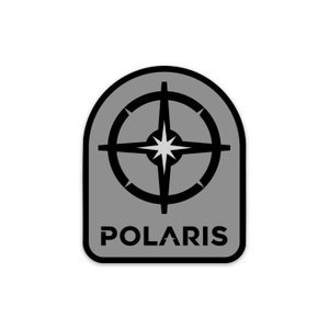 May include: A gray and black sticker with a compass and the word "POLARIS" in black text.
