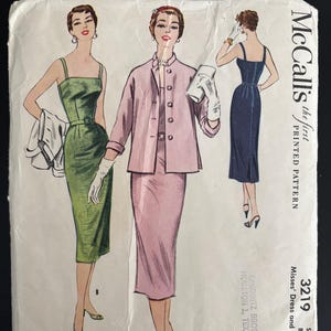 Op de afbeelding: Vintage McCall's naaipatroon met illustraties van drie jurken en een jasje. Het patroon bevat een groene jurk, een roze pak en een marineblauwe jurk. Het patroon is gelabeld "3219" en bevat de maat- en borstmaten.