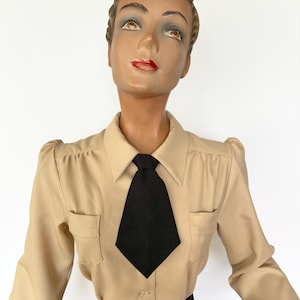 Op de afbeelding: Beige overhemd met knopen en een zwarte stropdas. Het overhemd heeft twee kleine borstzakken en een klassieke kraag. De stropdas is effen zwart en geknoopt. Het overhemd wordt op een mannequin gepresenteerd.