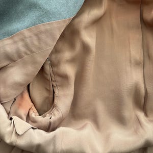 Puede incluir: Primer plano del interior de una blazer azul claro. El forro es de tela suave color melocot&oacute;n. Se aprecia la construcci&oacute;n de la blazer, con costuras y detalles de sastrer&iacute;a.