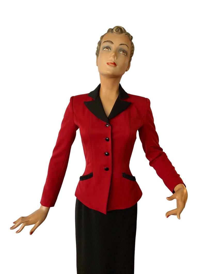 May include: A red blazer with a black collar and black buttons. The blazer has a fitted silhouette and is worn with a black skirt.