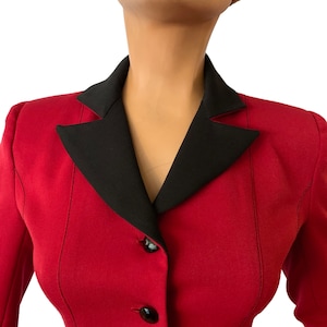 Puede incluir: Una chaqueta roja con cuello negro y cuatro botones negros. La chaqueta est&aacute; entallada y tiene una silueta ajustada.