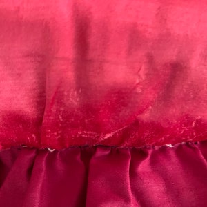 K&ouml;nnte beinhalten: Nahaufnahme eines tief roten Samtstoffes mit einem helleren roten Ombre-Effekt. Der Stoff hat einen dezenten Glanz und eine weiche Textur.