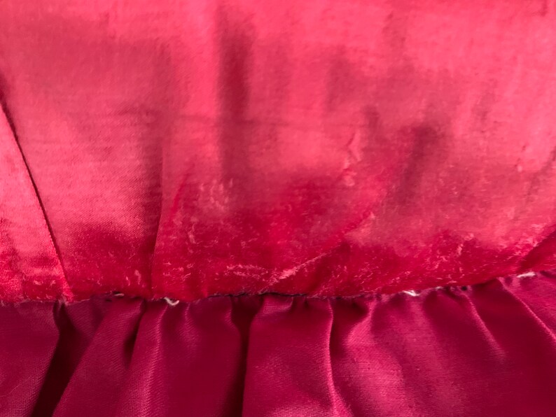K&ouml;nnte beinhalten: Nahaufnahme eines tief roten Samtstoffes mit einem helleren roten Ombre-Effekt. Der Stoff hat einen dezenten Glanz und eine weiche Textur.