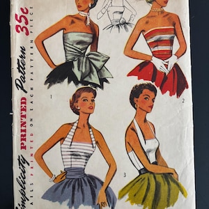 Op de afbeelding: Vintage Simplicity naaipatroon met illustraties van damesjurken. De omslag toont vier jurk ontwerpen, waaronder strapless en halter stijlen, met een prijs van 35c. Het patroon is maat 14, borstomvang 81 cm.