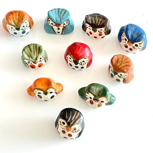 Puede incluir: Diez figuritas de búho de cerámica con pintura colorida y lunares. Los búhos son de varios colores, incluyendo naranja, azul, verde, rojo y negro.