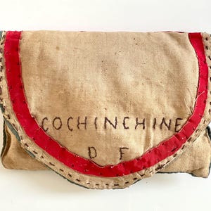 Może przedstawiać: Winietkowy worek z płótna z czerwonymi i niebieskimi lamówkami. Na przodzie worka wyszyte są słowa "COCHINCHINE D F".