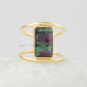 May include: Gold ring with a rectangular green and pink gemstone set in a double band.