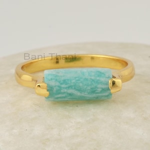 Peut inclure: Une bague en or avec une pierre rectangulaire bleu clair. La pierre a un motif marbré.