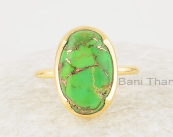 Könnte beinhalten: Ein goldener Ring mit einem ovalen, grünen Türkis-Stein, der in einer Zargenfassung gefasst ist. Der Ring befindet sich auf einem weißen Hintergrund.