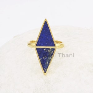 Puede incluir: Un anillo de oro con una piedra preciosa de lapislázuli azul en forma de diamante geométrico.