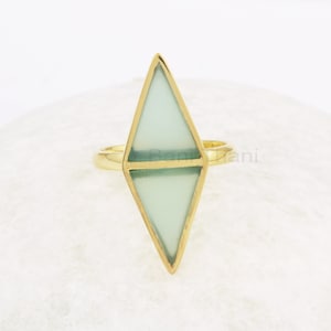 Pode incluir: Um anel de ouro com uma gema geométrica verde claro em forma de diamante.