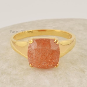 Könnte beinhalten: Ein goldener Ring mit einem quadratischen Sonnenstein. Der Ring ist in einer schlichten Fassung gefasst.