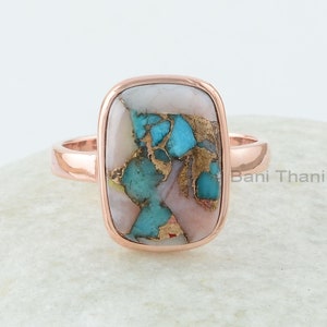 Puede incluir: Un anillo de oro rosa con una piedra rectangular turquesa y rosa. La piedra tiene un patrón único de turquesa y rosa.