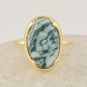 Op de afbeelding: Gouden ring met een ovale groene en witte agaat edelsteen. De ring heeft een eenvoudige band en een bezel setting.