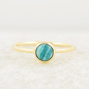 Puede incluir: Un anillo de oro con una piedra ovalada de color azul claro.