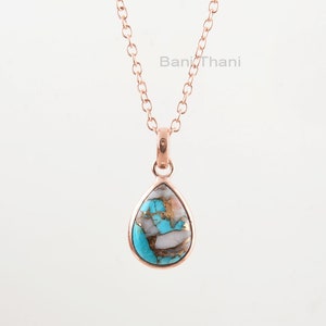 May include: A rose gold chain necklace with a teardrop-shaped pendant featuring a turquoise and white stone.