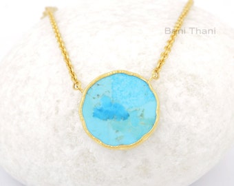 Peut inclure: Un collier en chaîne dorée avec un grand pendentif rond en turquoise. La pierre est de couleur bleu clair avec des veines bleu foncé qui la traversent. Le pendentif est serti dans une monture en or.