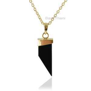 May include: A gold chain necklace with a black gemstone pendant. The pendant is shaped like a triangle with a gold trim.