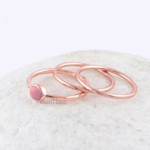 Könnte beinhalten: Ein Set aus drei Ringen aus Roségold, einer mit einem rosafarbenen Stein, auf weißem Hintergrund.