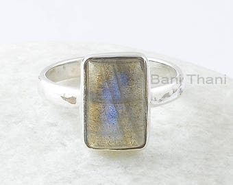 May include: A silver ring with a rectangular labradorite gemstone. The ring has a textured band.