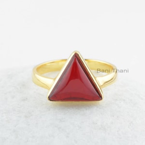 May include: Gold ring with a triangular red gemstone.