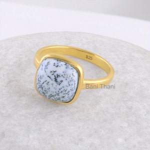 May include: A gold ring with a square-shaped white and black dendritic agate gemstone. The ring is stamped with "925" and "Bani Thani".