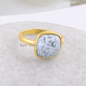 May include: A gold ring with a square-shaped white and black dendritic agate gemstone. The ring is marked with "925" on the band.