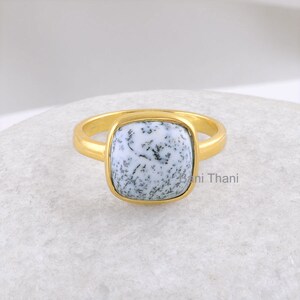 May include: A gold ring with a square white and black dendritic agate gemstone.