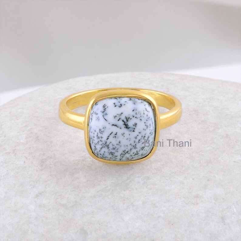 May include: A gold ring with a square white and black dendritic agate gemstone.