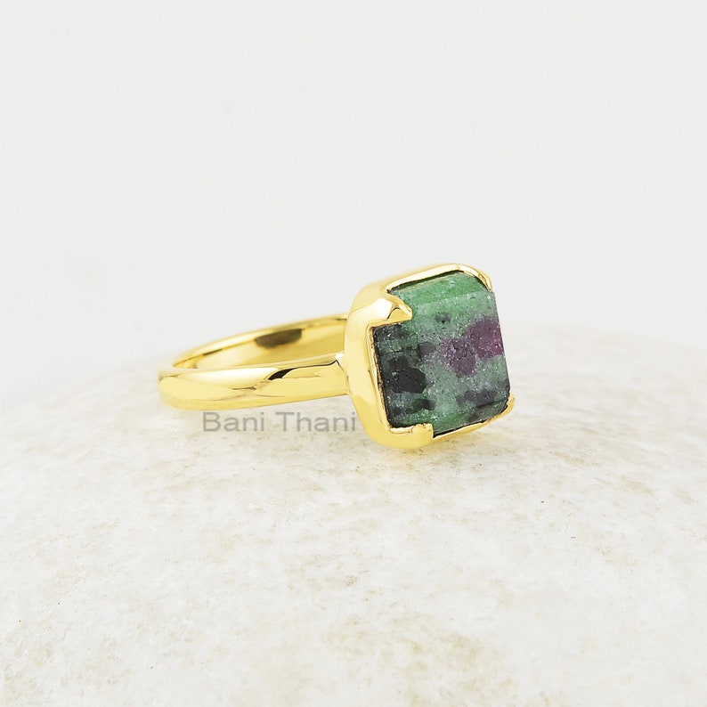 Puede incluir: Anillo de oro con una piedra preciosa verde y morada. El anillo est&aacute; engastado en una forma cuadrada y tiene un acabado liso y pulido.
