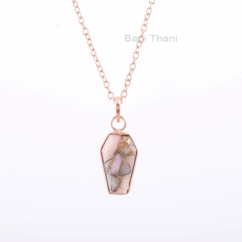 K&ouml;nnte beinhalten: Eine Halskette aus ros&eacute;goldener Kette mit einem ros&eacute;goldenen und goldenen Anh&auml;nger in Sargform. Der Anh&auml;nger ist aus einem ros&eacute;goldenen und goldenen Stein gefertigt.
