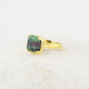Puede incluir: Anillo de oro con una piedra preciosa cuadrada verde y rosa. El anillo est&aacute; engastado en una banda de oro y tiene un engaste cuadrado. La piedra preciosa es una zoisita verde y rosa.