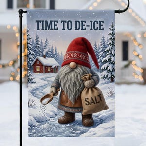 May include: A rectangular garden flag featuring a gnome with a long gray beard and a red hat, holding a wooden scoop and a burlap sack labeled SALT. The text TIME TO DE-ICE is printed at the top, with a snowy winter landscape and a red house.