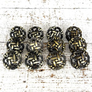 Puede incluir: Ocho pomos de armario de latón antiguo con un diseño tejido. Los pomos están dispuestos en dos filas de cuatro sobre una superficie de madera blanca.