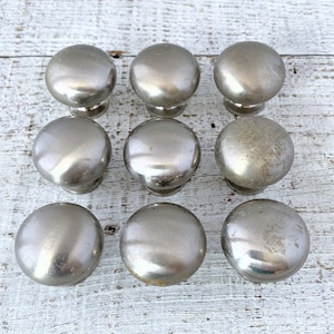 May include: Ten silver round cabinet knobs with a smooth, shiny finish.